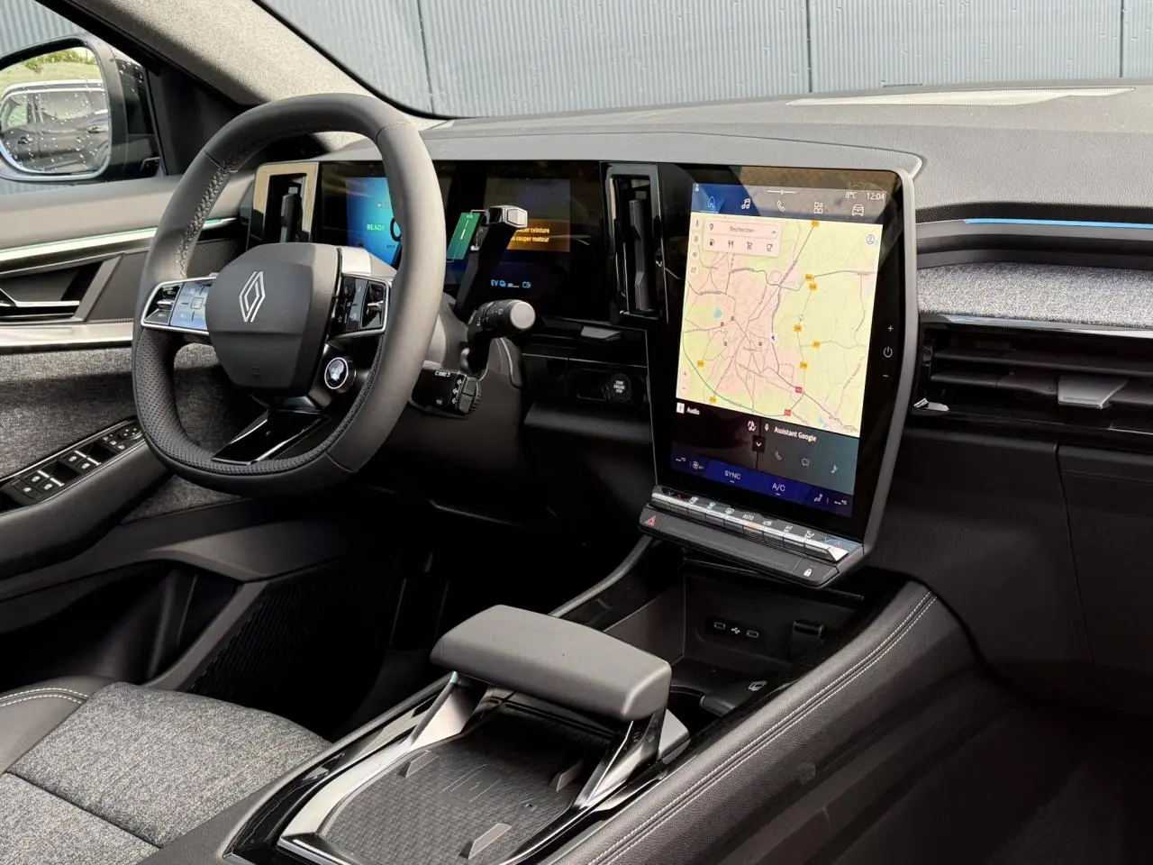 Vue intérieure côté conducteur du Renault Espace VI hybride, avec grand écran tactile vertical et volant cuir noir.