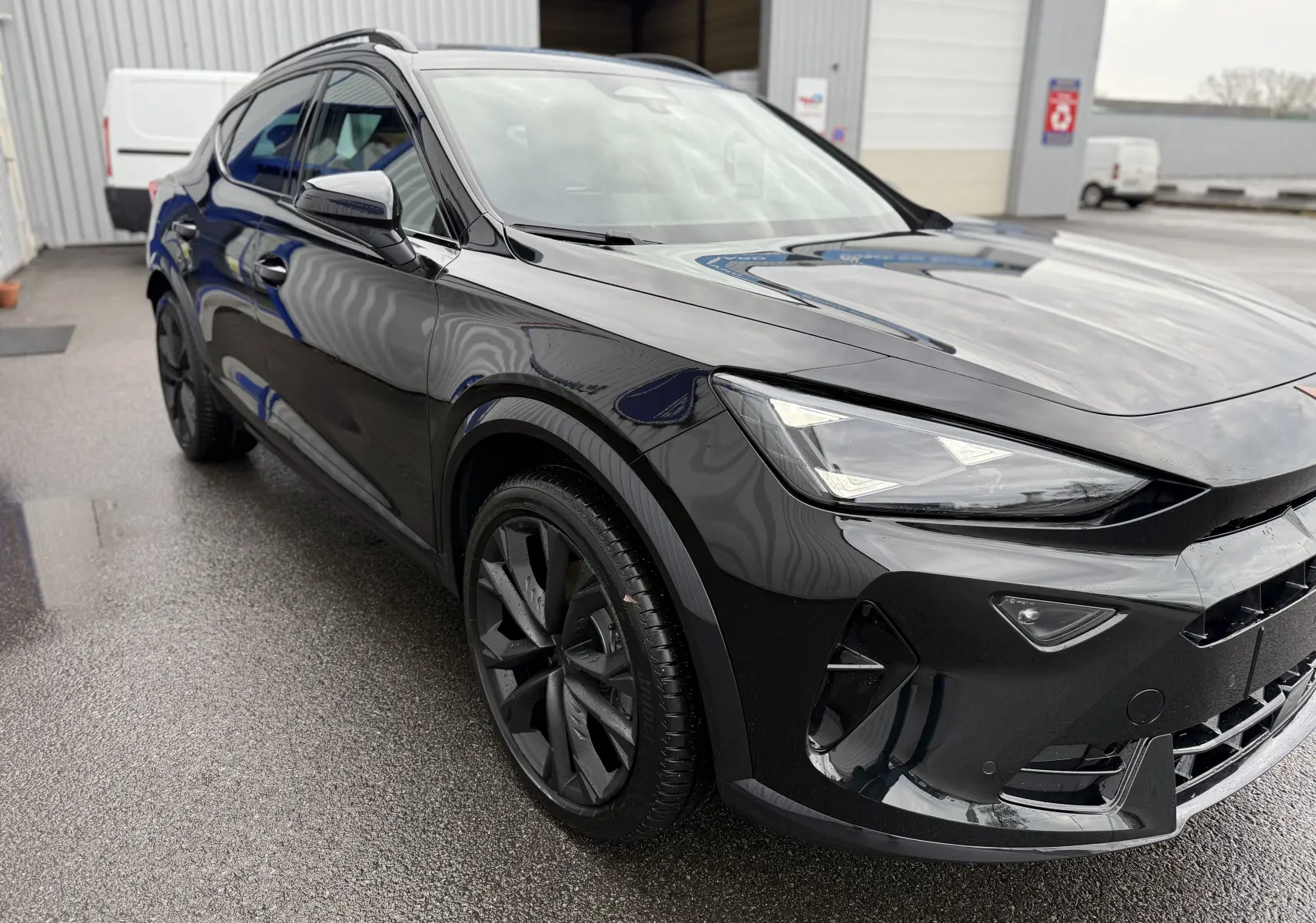 Vue 3/4 avant gauche d’un CUPRA Formentor 1.5 eHybrid 204 noir minuit avec jantes noires et phares LED allumés.