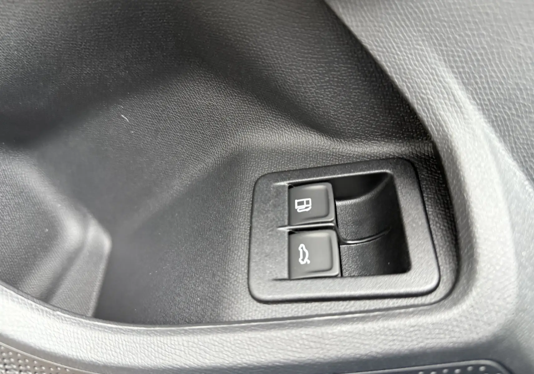 Gros plan sur les boutons d'ouverture de la trappe à carburant et du coffre dans l'habitacle noir du CUPRA Formentor.