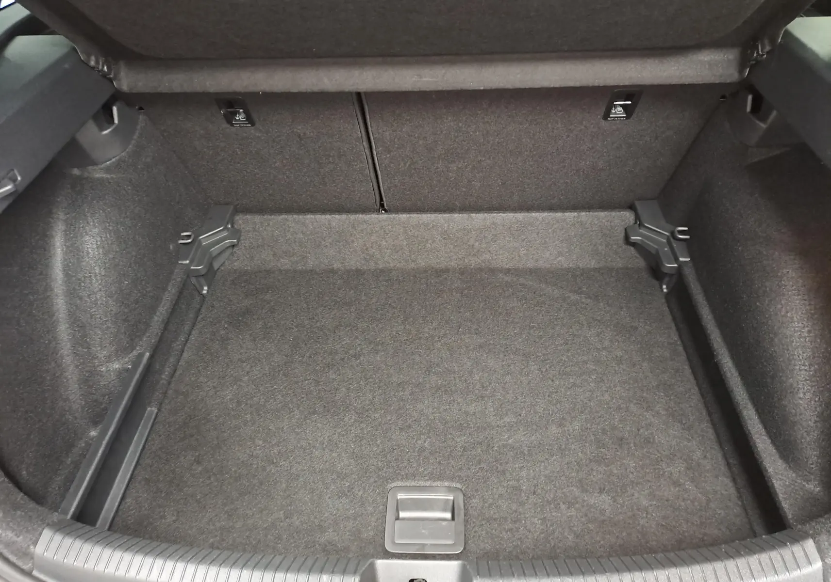 Coffre vide vu de l'intérieur, revêtement gris foncé, sans objet ni accessoire visible.