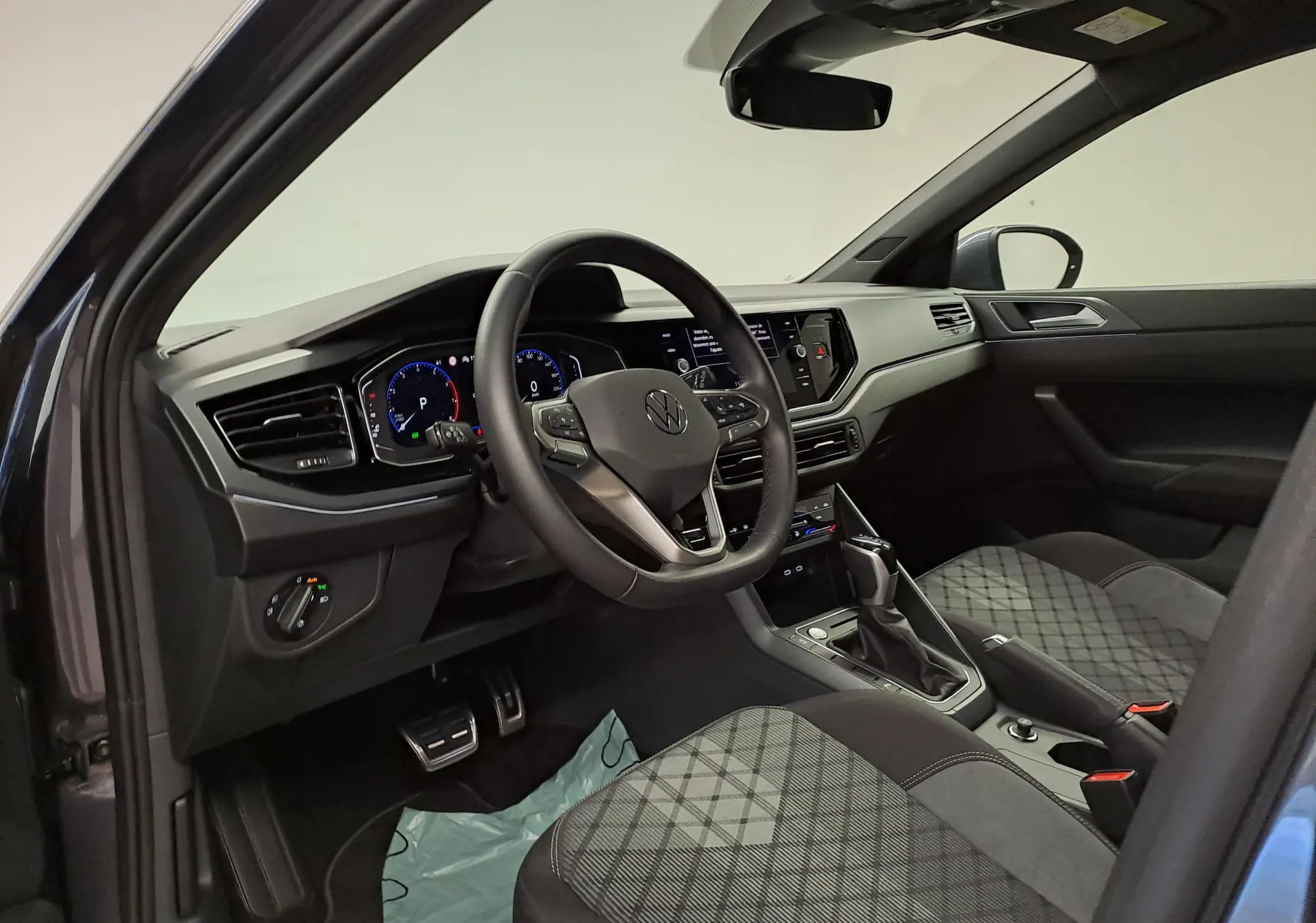 Vue intérieure côté conducteur du Volkswagen Taigo 1.0 TSI R-Line Edition avec volant multifonction et sièges tissu à motif gris.