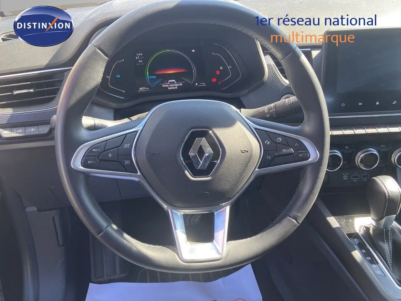 Vue rapprochée du volant noir de la Renault Arkana hybride 2023 avec tableau de bord numérique et console centrale visible.