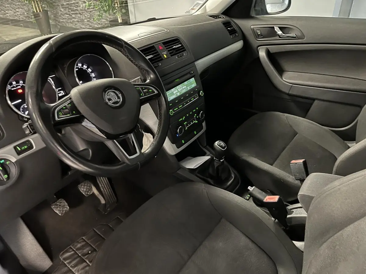 Intérieur noir du Skoda Yeti 2015 vu côté conducteur, volant cuir multifonctions et boîte manuelle visible.