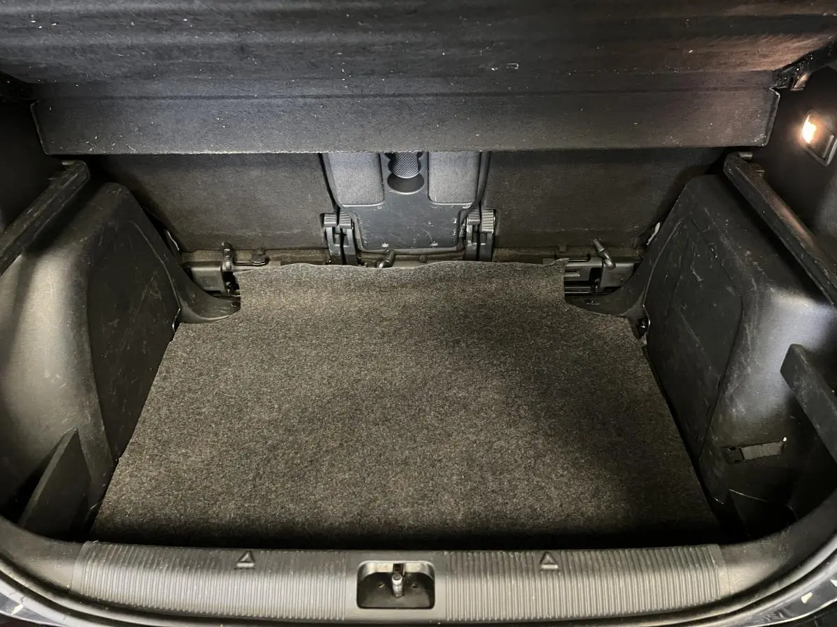 Coffre spacieux du Skoda Yeti 2015 vu de face, avec tapis gris et éclairage intérieur à droite.