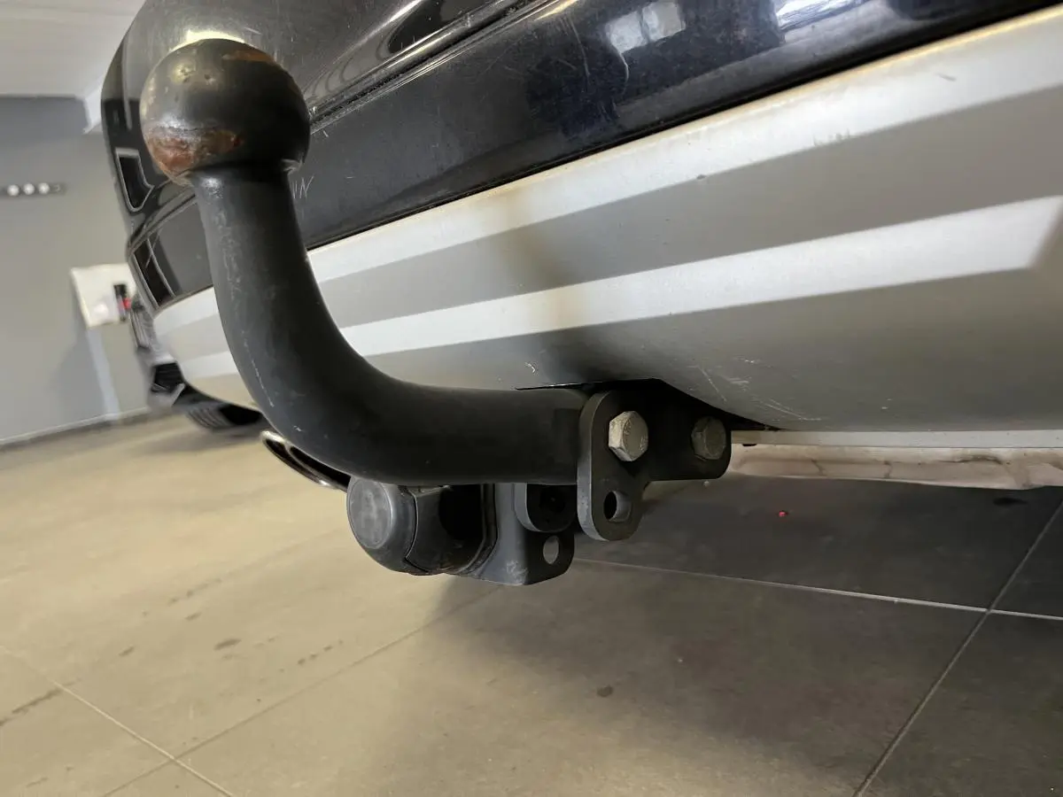 Gros plan sur l'attelage noir fixé au pare-chocs arrière gris clair d'un Skoda Yeti noir.