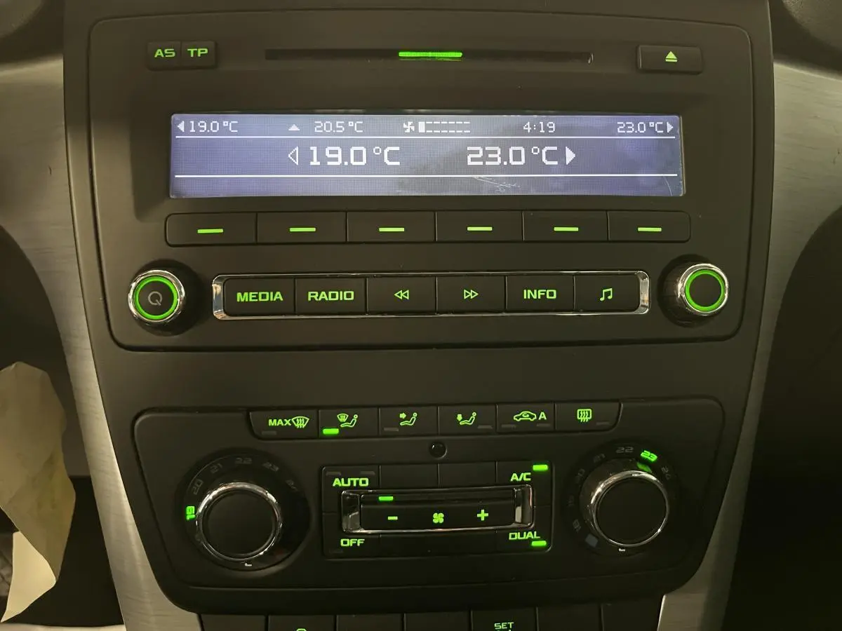 Tableau de bord du Skoda Yeti 2015 montrant la console centrale avec climatisation automatique bi-zone et commandes audio éclairées en vert