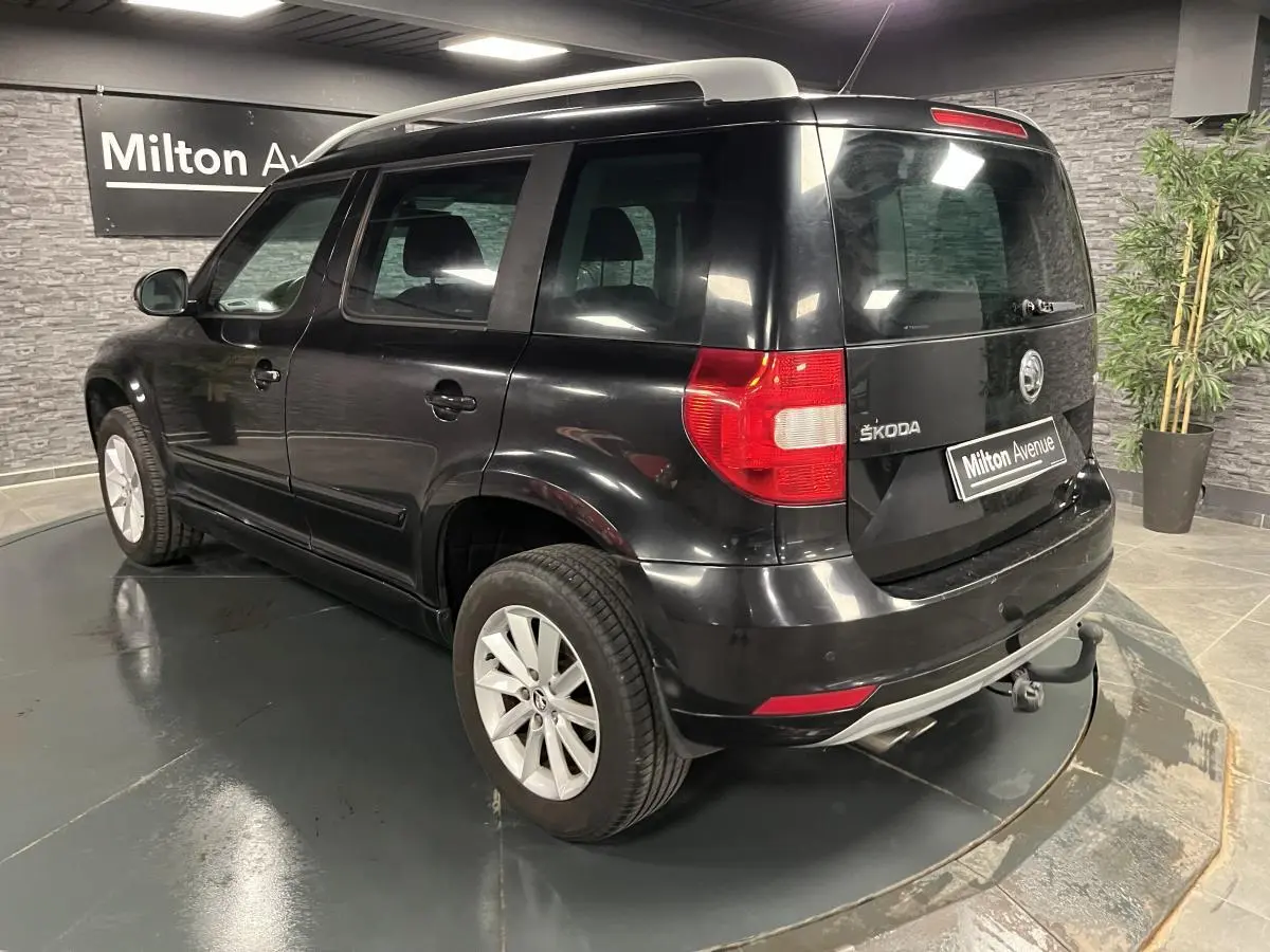 Vue 3/4 arrière droite d'un Skoda Yeti noir avec attelage et jantes alliage 16 pouces dans un showroom.