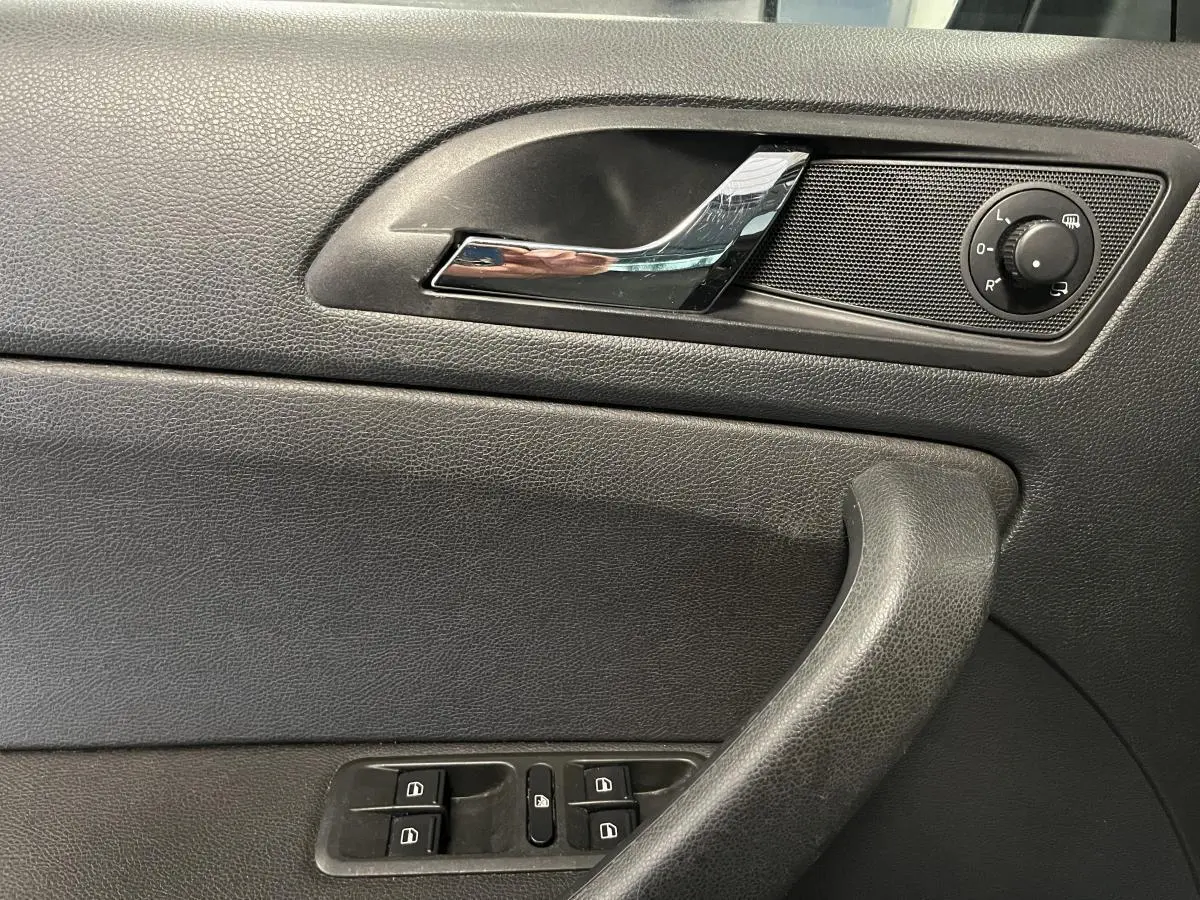 Détail de la porte côté conducteur du Skoda Yeti 2015 noire, avec commandes des vitres et réglage des rétroviseurs.