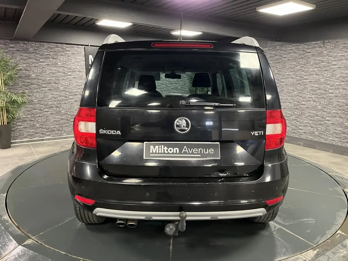 Vue arrière d'un Skoda Yeti noir 2015 avec attelage et double sortie d'échappement visible en intérieur showroom.
