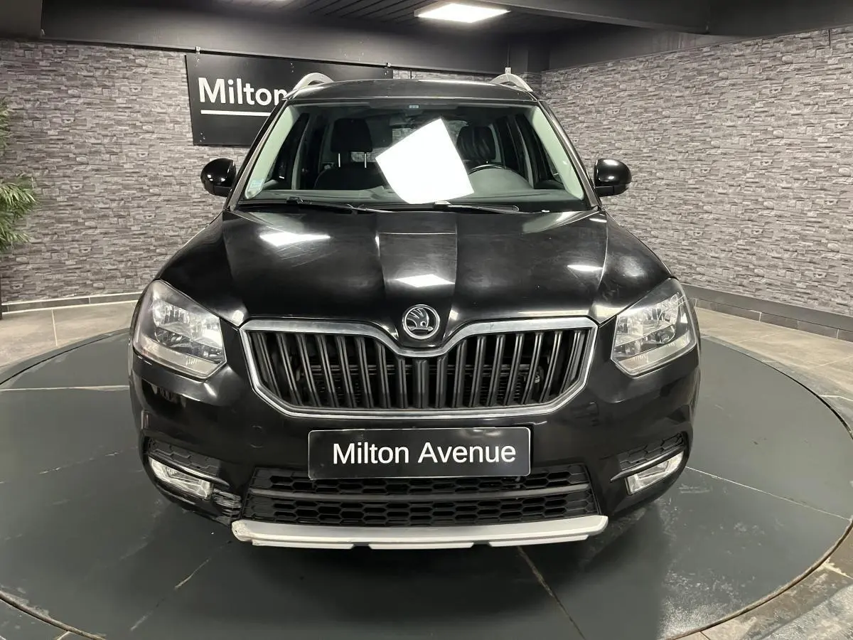 Vue frontale d'un Skoda Yeti noir avec calandre chromée et plaques "Milton Avenue" en intérieur showroom.