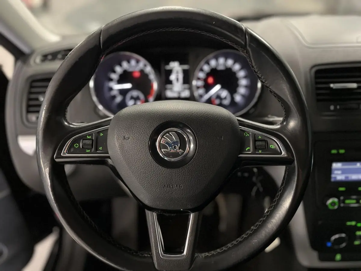 Volant cuir multifonctions noir de Skoda Yeti 2015 vu de face avec tableau de bord flou en arrière-plan.