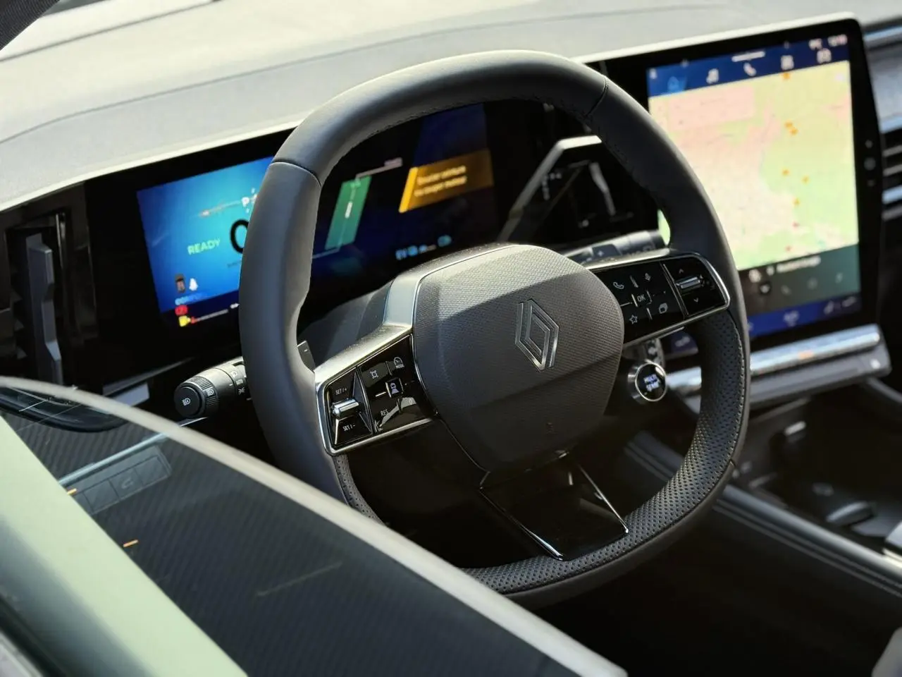 Volant noir au design moderne avec logo Renault, tableau de bord numérique et écran tactile central du Renault Espace 2025.