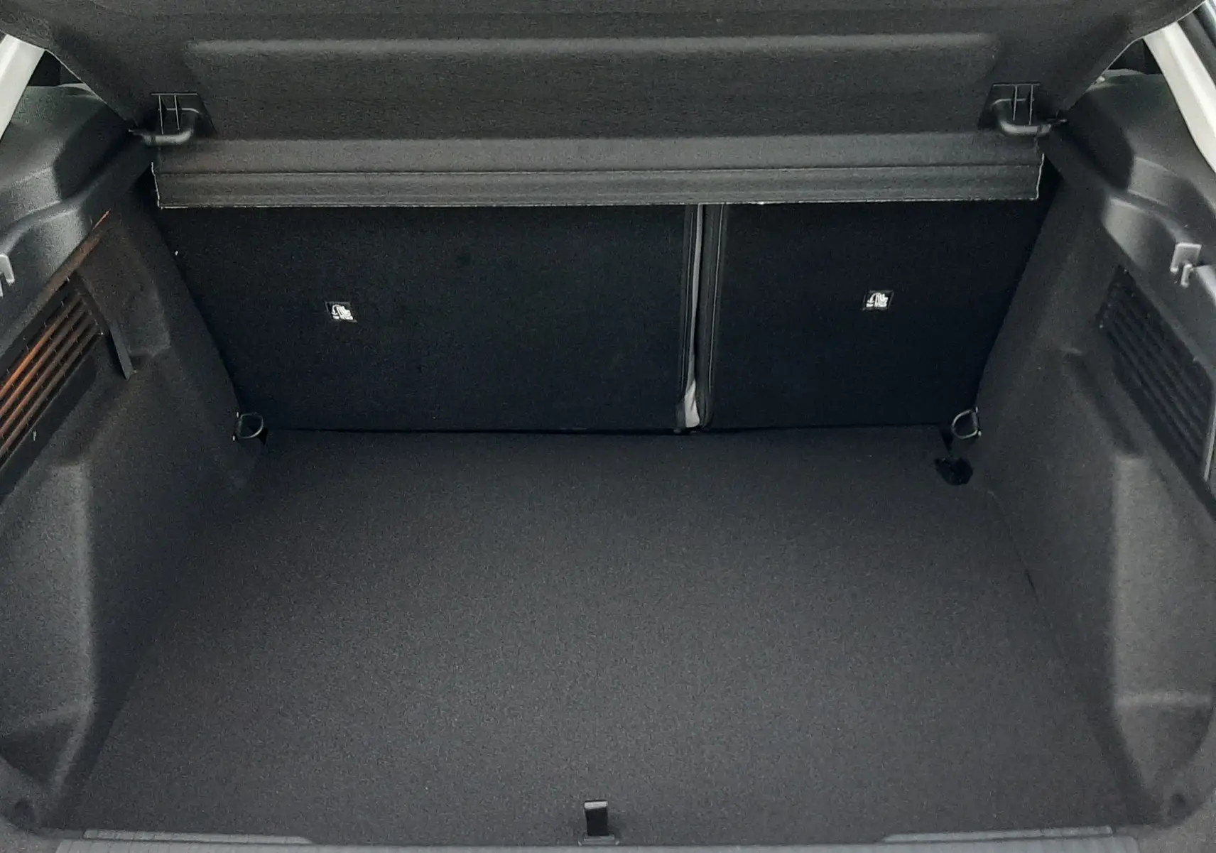 Coffre ouvert vu de l'arrière d'une Citroën C4 1.2 Hybride 145ch blanc Okenite avec toit noir Perla, intérieur noir.