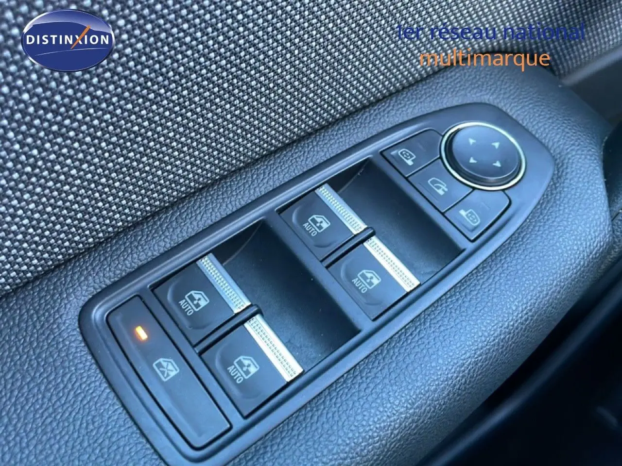 Gros plan sur les commandes des vitres électriques côté conducteur du Renault Captur rouge désir métal avec toit noir.