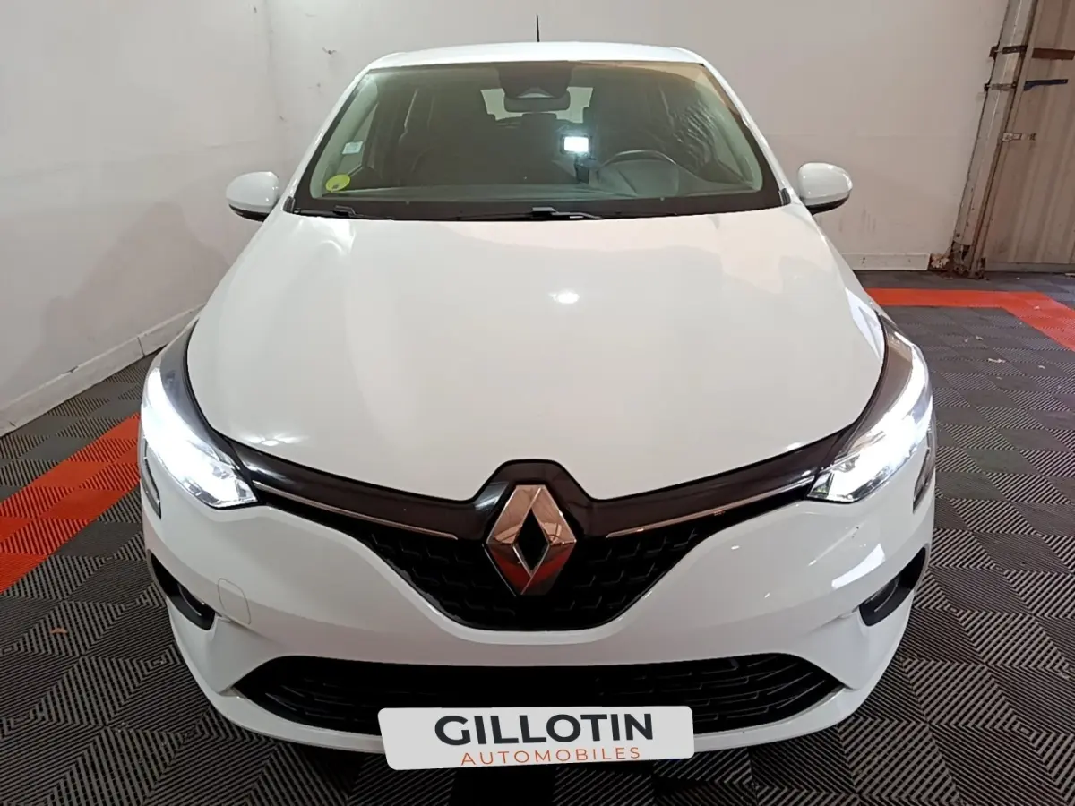 Vue avant d'une Renault Clio Business Blue dCi 85 blanche avec phares LED allumés dans un garage.