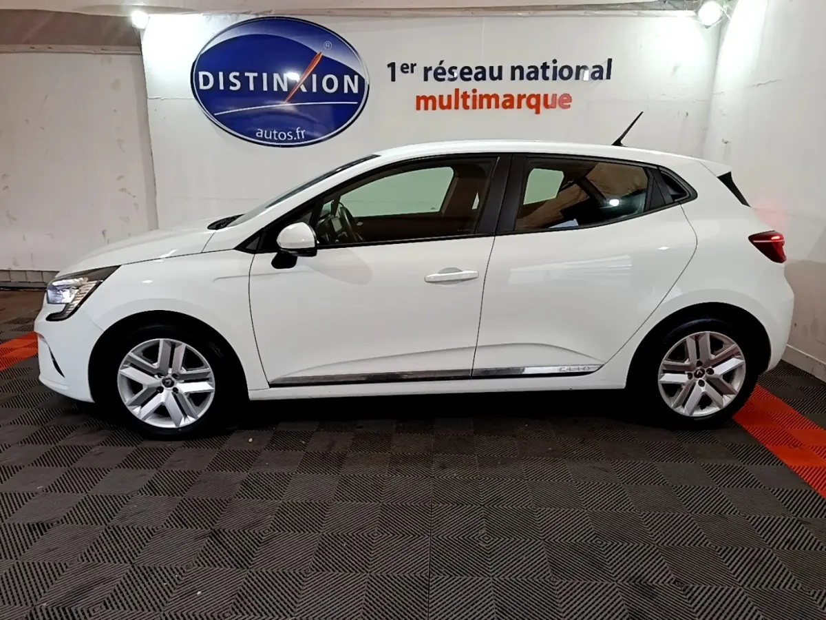 Profil côté gauche d'une Renault Clio Business Blue dCi 85 blanche, avec jantes alliage et logo Distinxion en arrière-plan.