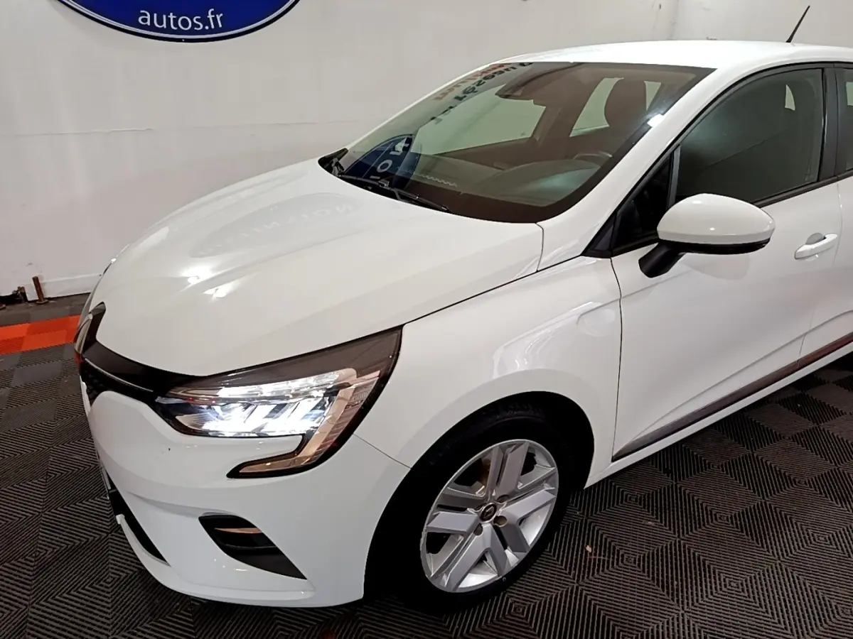 Renault Clio Business blanc vue 3/4 avant droit, phares LED allumés et jantes alliage visibles.