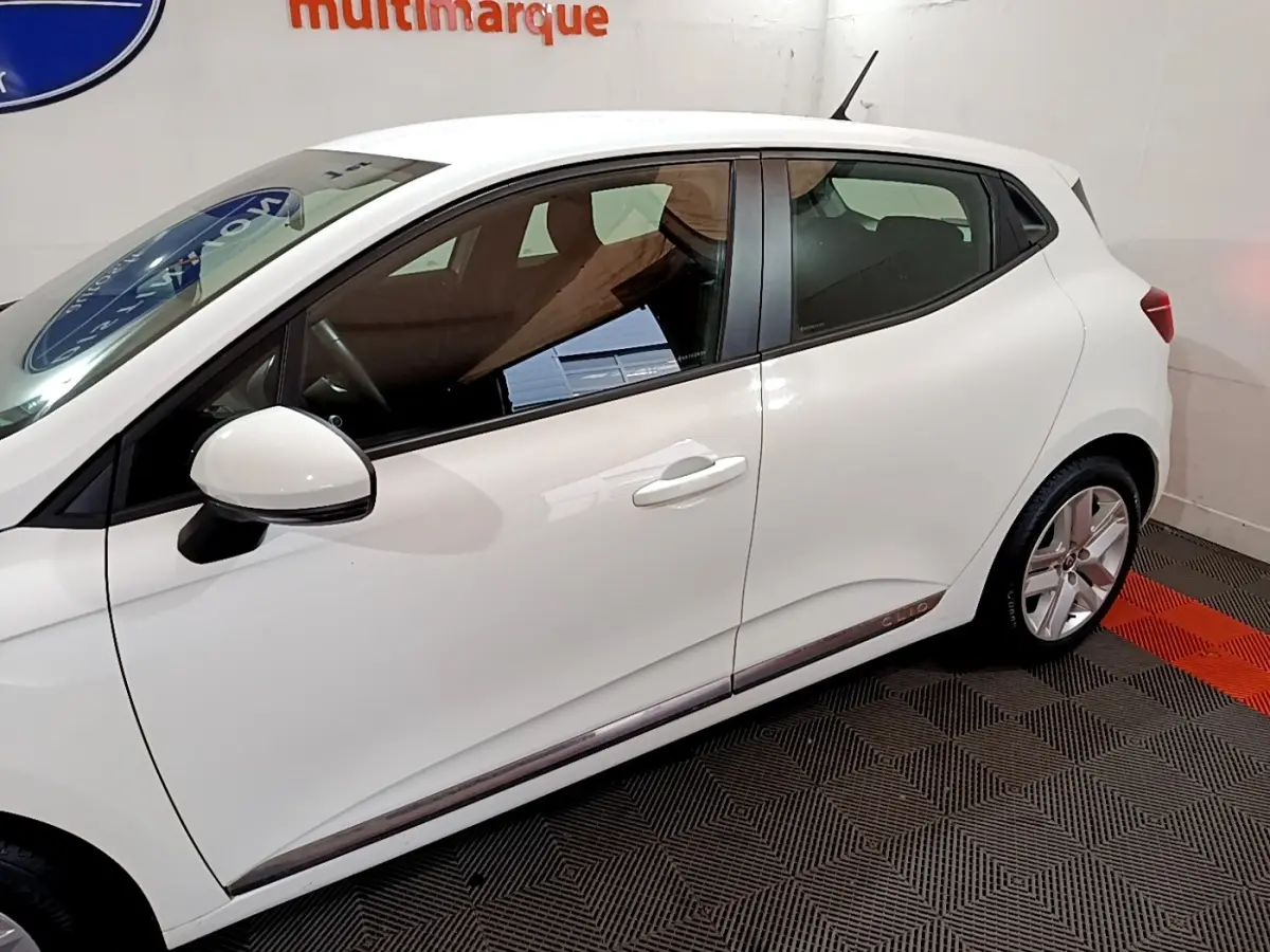 Profil côté gauche d'une Renault Clio Business Blue dCi 85 blanche, avec jantes alliage et poignées de porte assorties.