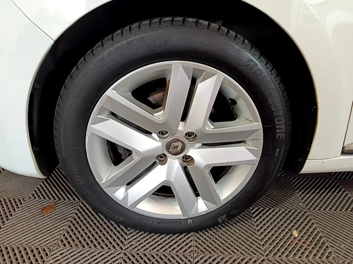 Gros plan sur la roue avant gauche blanche d'une Renault Clio Business Blue dCi 85 avec jante alliage moderne.