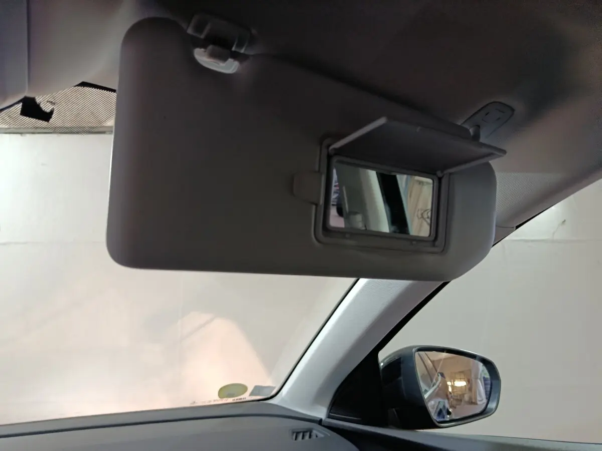 Miroir de courtoisie ouvert sur pare-soleil côté conducteur dans l'habitacle clair d'un Peugeot 3008 2020.