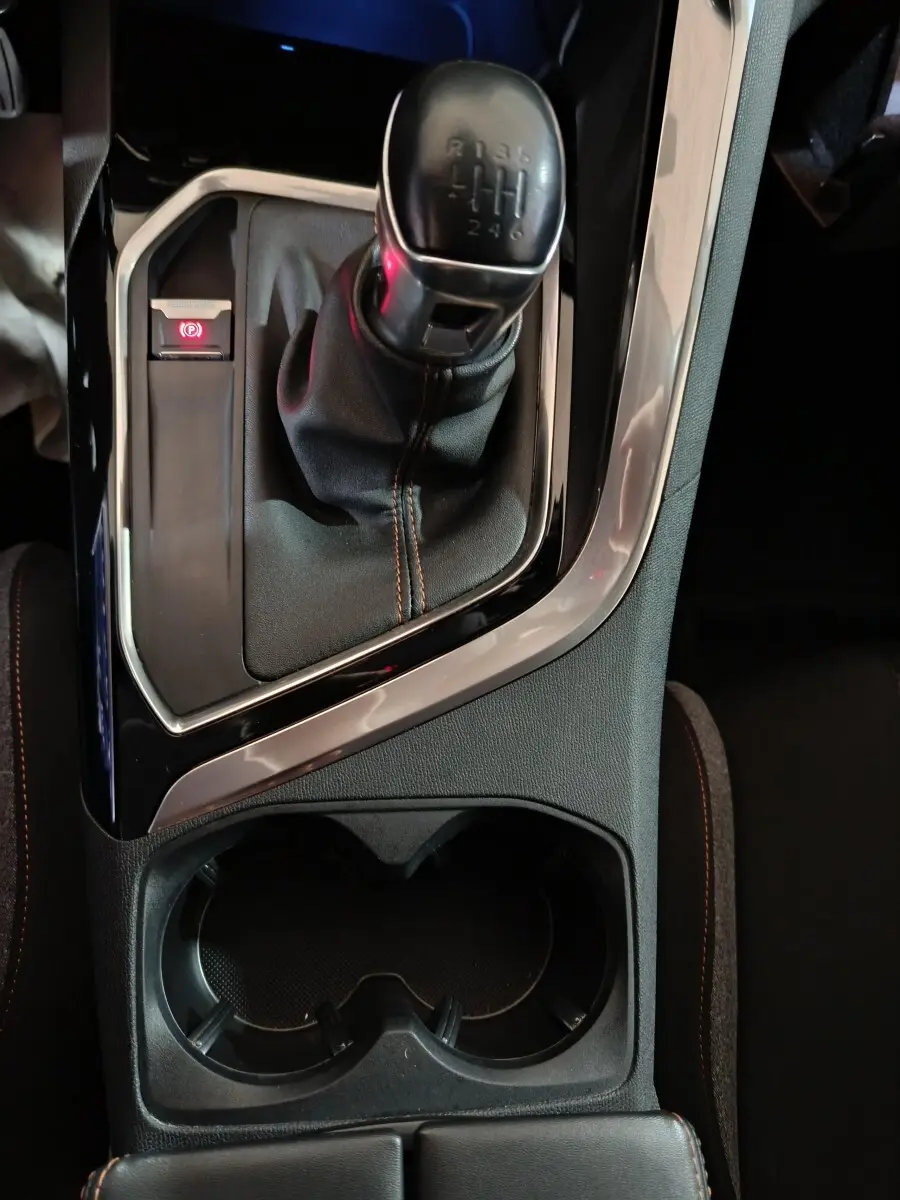 Gros plan sur la commande de boîte manuelle et frein à main électrique dans l'habitacle sombre du Peugeot 3008 2020.