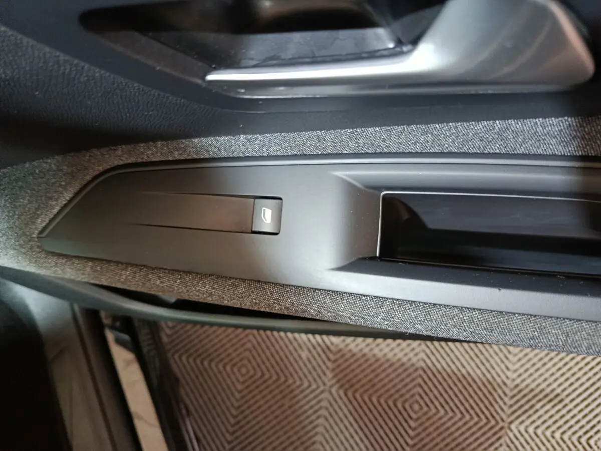 Gros plan sur la commande de lève-vitre côté conducteur du Peugeot 3008 2020, intérieur noir et tissu gris.