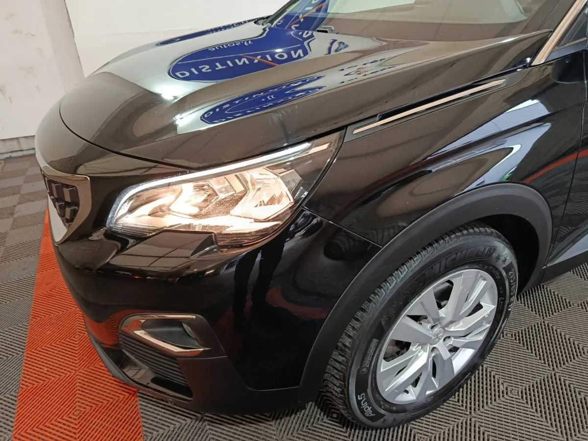 Gros plan sur l'avant droit noir brillant du Peugeot 3008 avec phare allumé et jante alu visible.