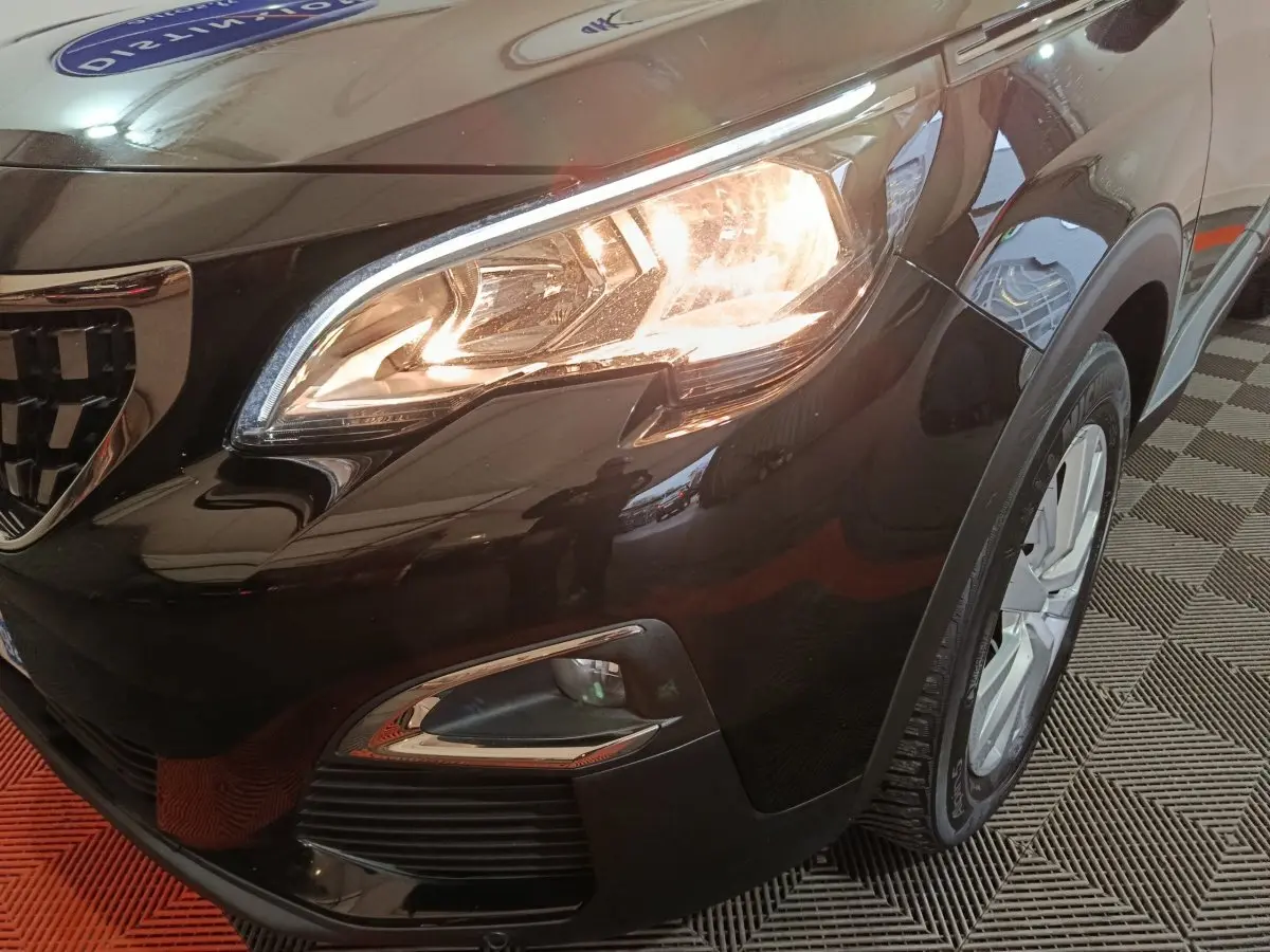 Gros plan sur l'avant droit noir brillant du Peugeot 3008 2020 avec phare allumé et jante visible.