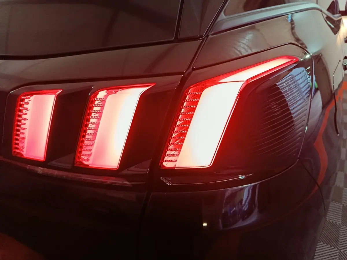 Gros plan sur les feux arrière droits rouges allumés d’un Peugeot 3008 2020 couleur foncée.