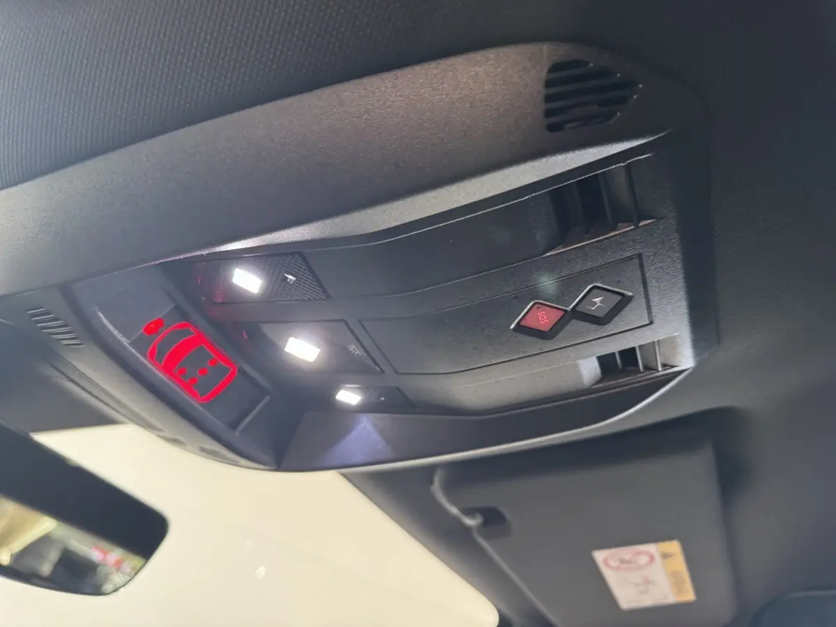 Vue intérieure en gros plan du plafonnier avec boutons SOS et éclairage, dans un DS7 Crossback gris foncé.