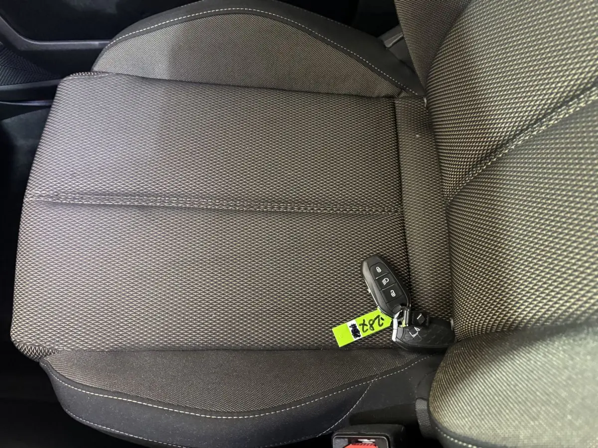 Gros plan sur la sellerie tissu gris foncé du siège avant droit avec clé de voiture posée dessus.