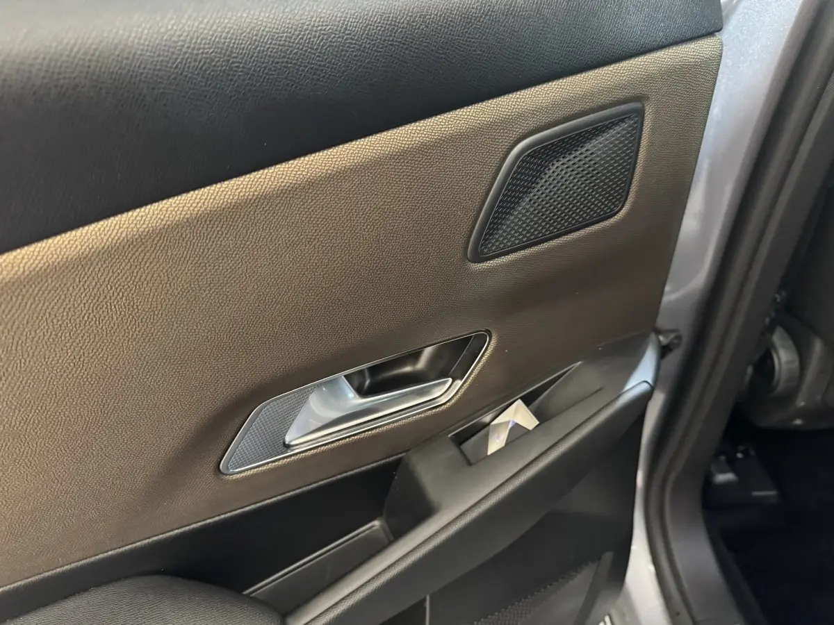 Détail de la porte arrière droite du DS7 Crossback gris foncé, montrant la poignée intérieure et le haut-parleur intégré.