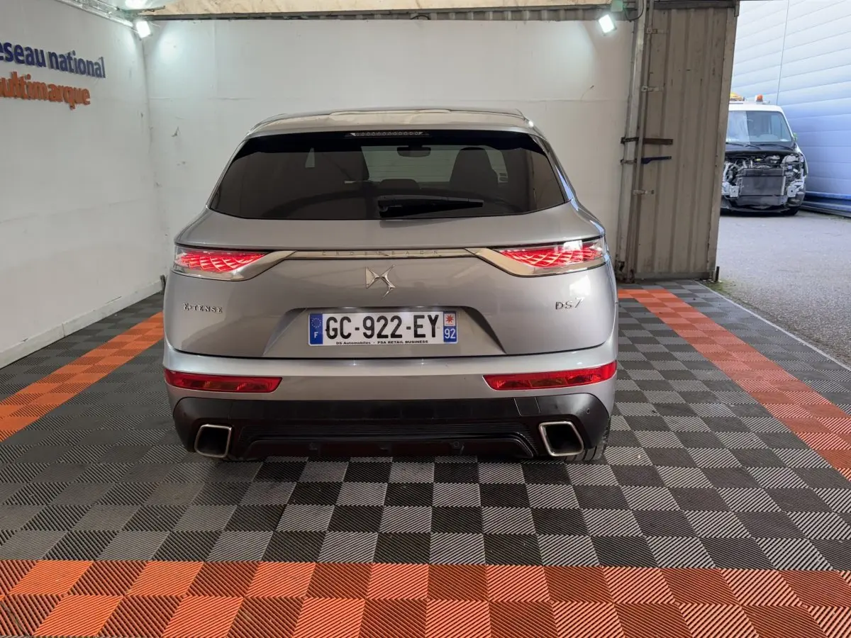 Vue arrière du DS7 Crossback E-TENSE gris foncé avec feux LED allumés et double sortie d’échappement carrée.