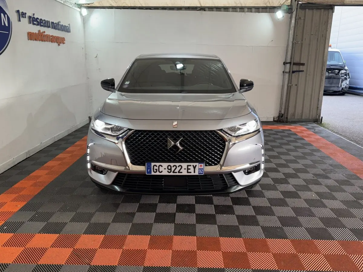 Vue frontale d’un DS7 Crossback E-TENSE 225 Bastille+ gris foncé avec calandre noire et phares allumés.