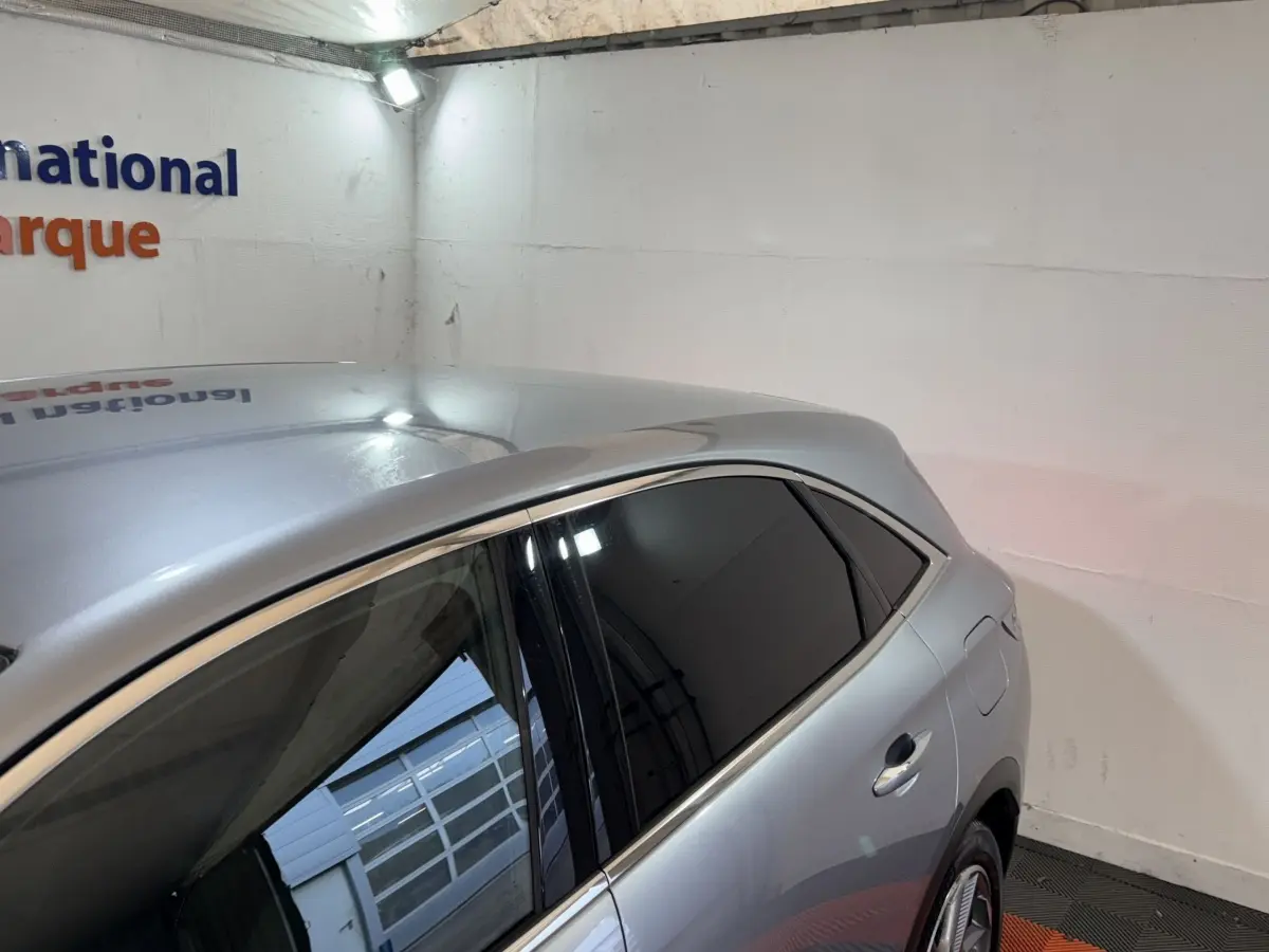 Vue 3/4 arrière côté droit du DS7 Crossback gris foncé avec vitres teintées et lignes de toit élancées.