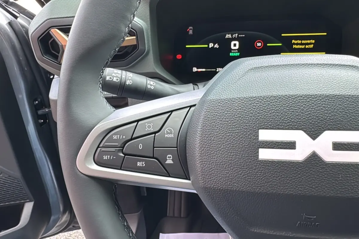 Gros plan sur le volant cuir gris et les commandes multifonctions du Dacia Bigster Hybrid 155 Extreme Plus, intérieur gris schiste.