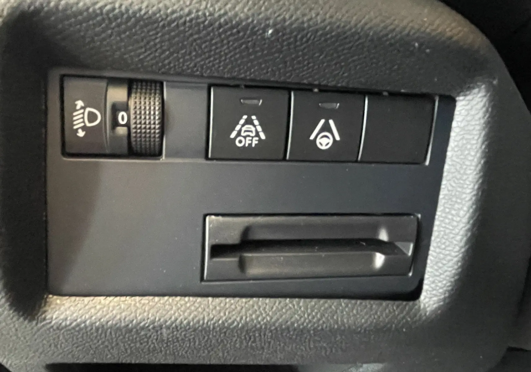 Gros plan sur les commandes d'assistance à la conduite et réglage des phares du Citroën C5 Aircross hybride 2025.