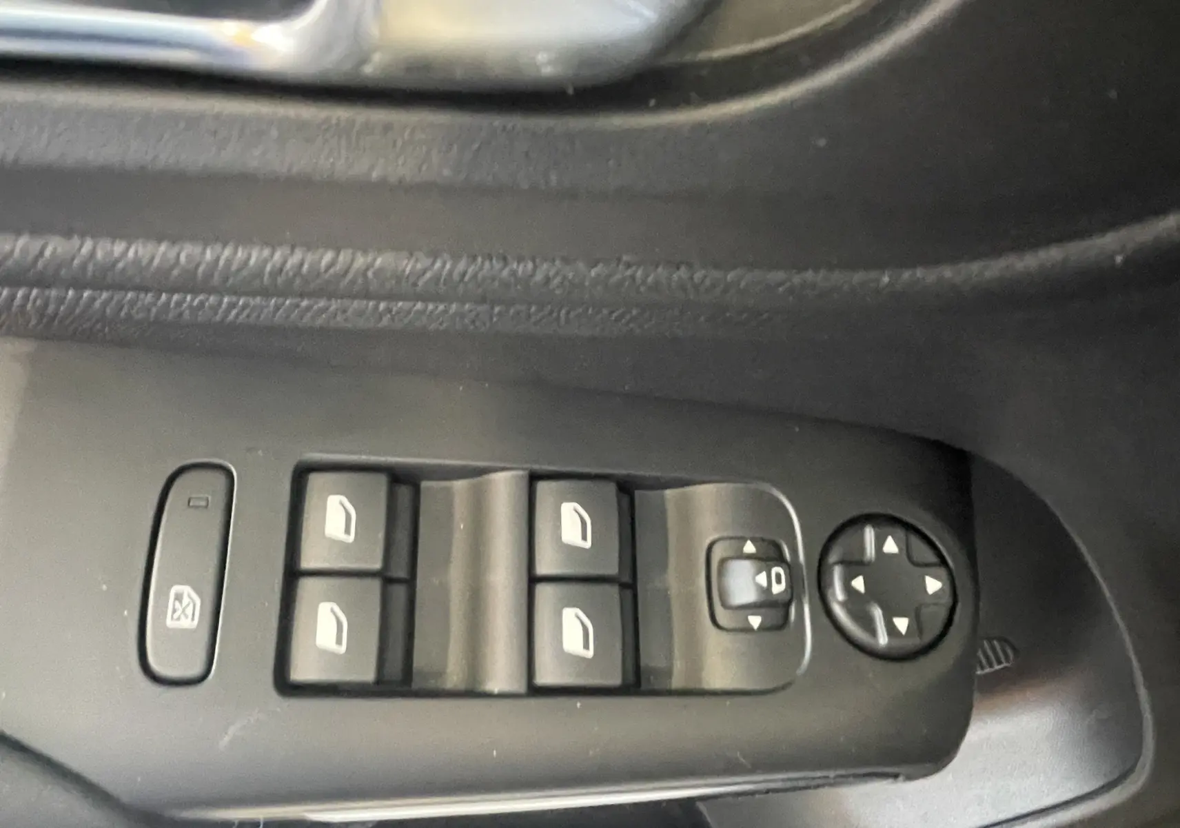 Gros plan sur les commandes de lève-vitres et réglage des rétroviseurs côté conducteur d'une Citroën C5 Aircross hybride bleu foncé.