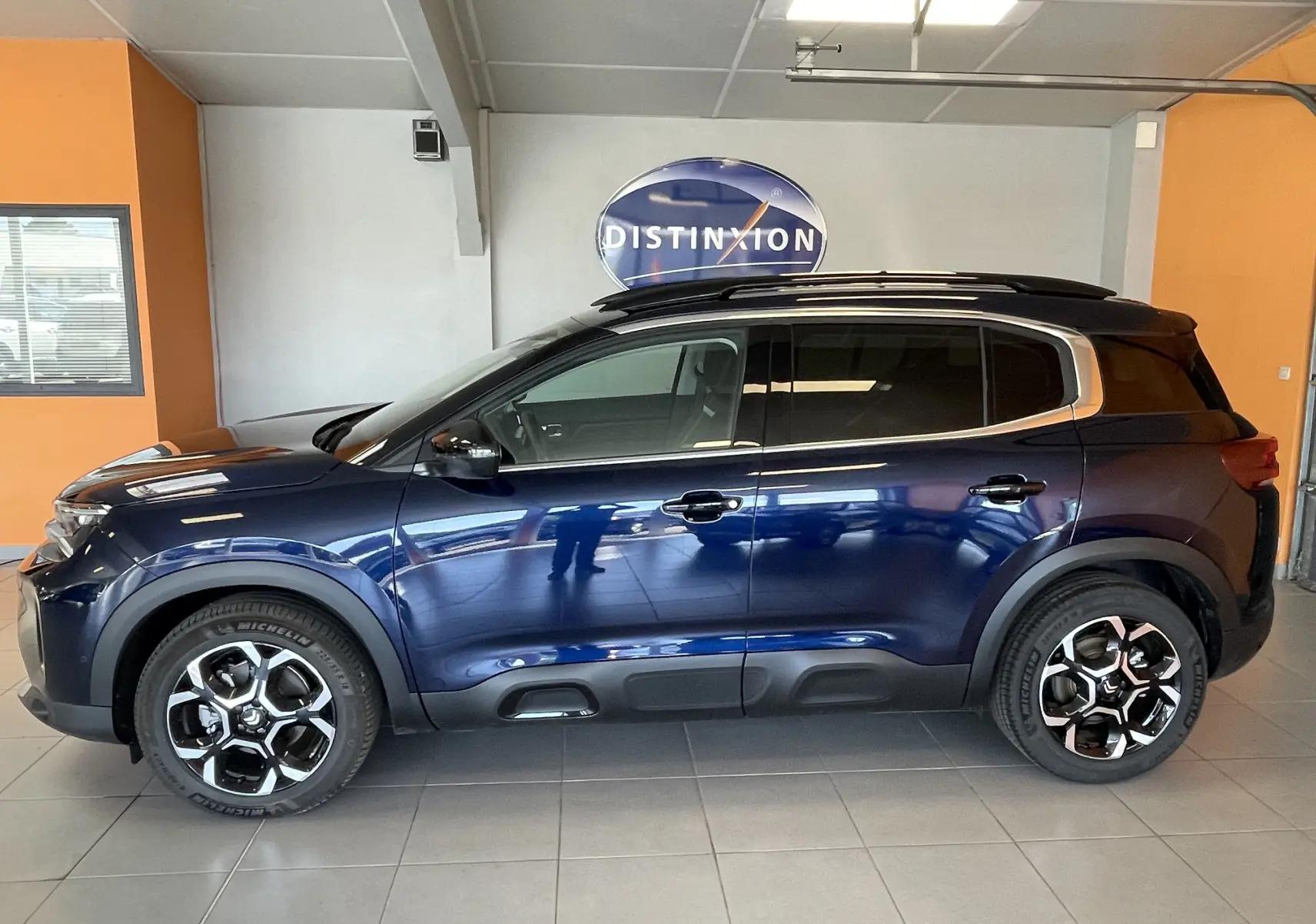 Vue de profil droit du Citroën C5 Aircross hybride 2025 bleu foncé, avec jantes alliage 18 pouces biton et vitres arrière surteintées.