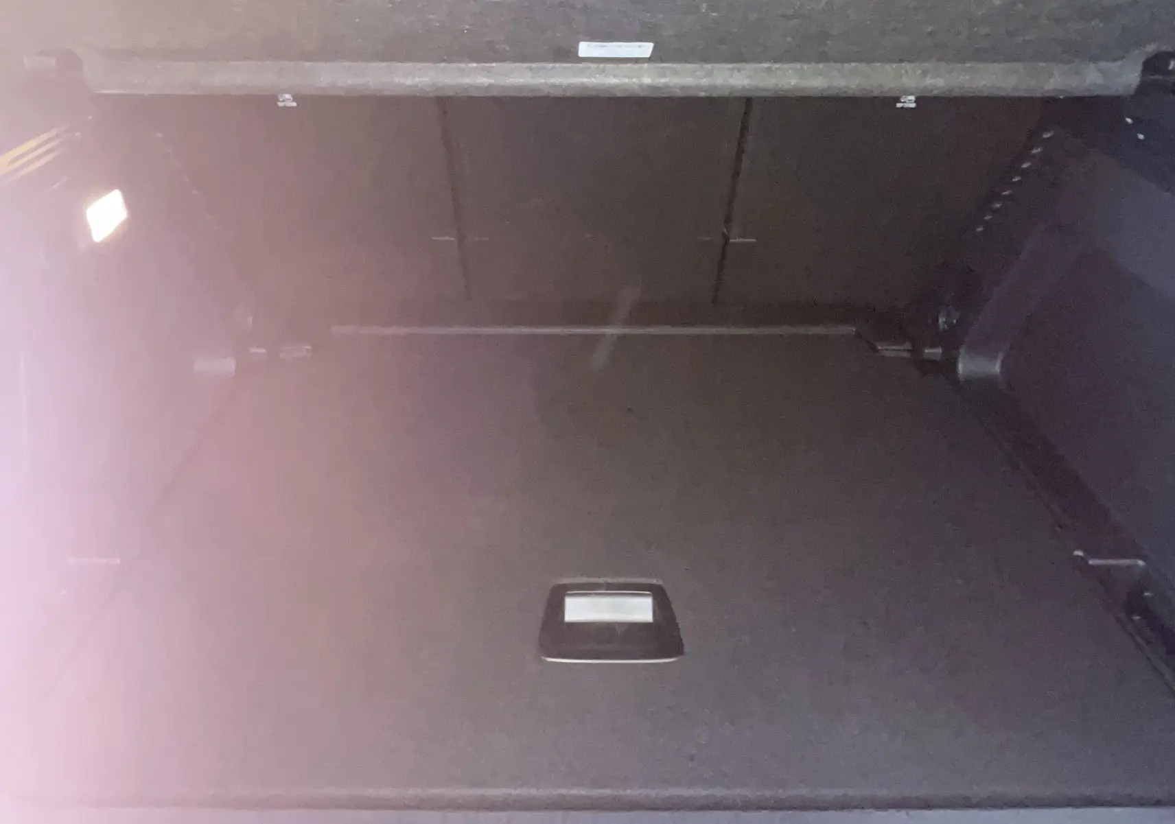 Coffre ouvert vu de face du Citroën C5 Aircross hybride 2025 en bleu foncé, espace de chargement vide et éclairé.