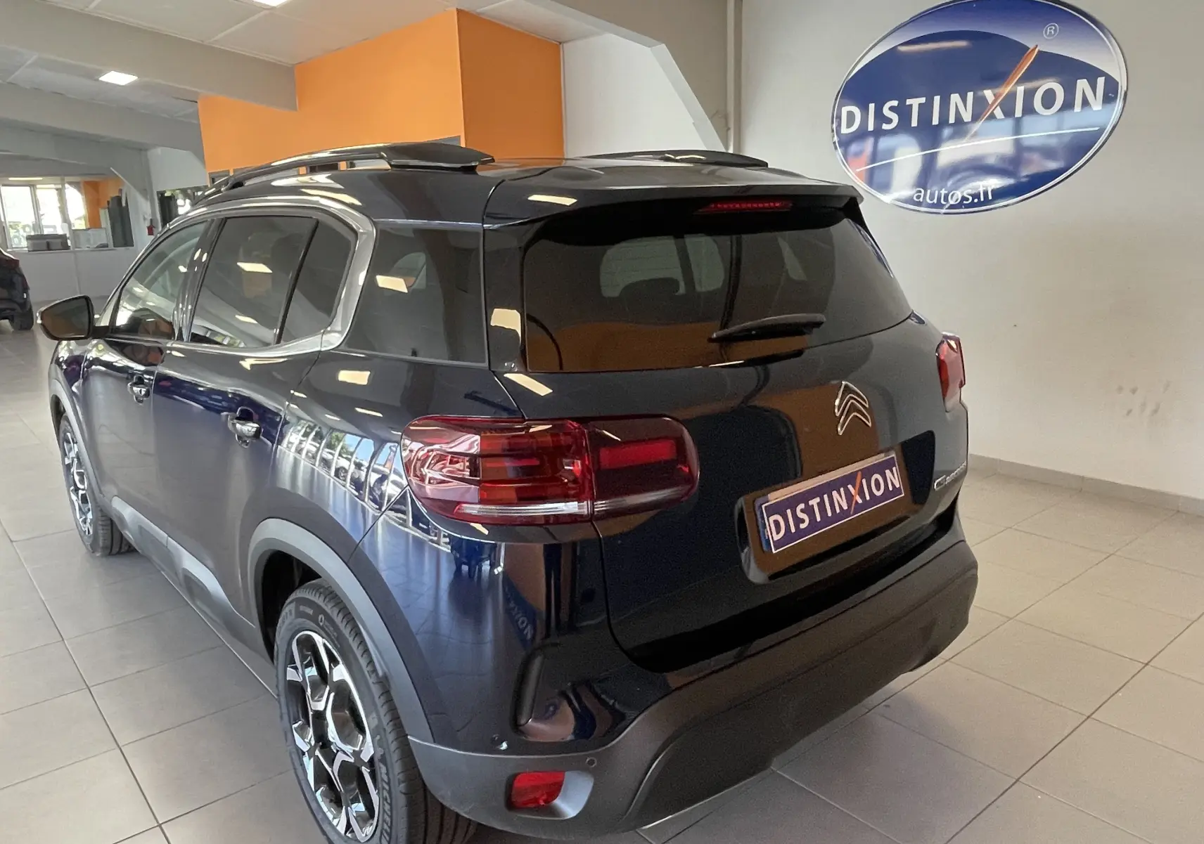 Vue 3/4 arrière droite du Citroën C5 Aircross hybride 2025 bleu foncé avec jantes alliage 18 pouces biton en showroom.