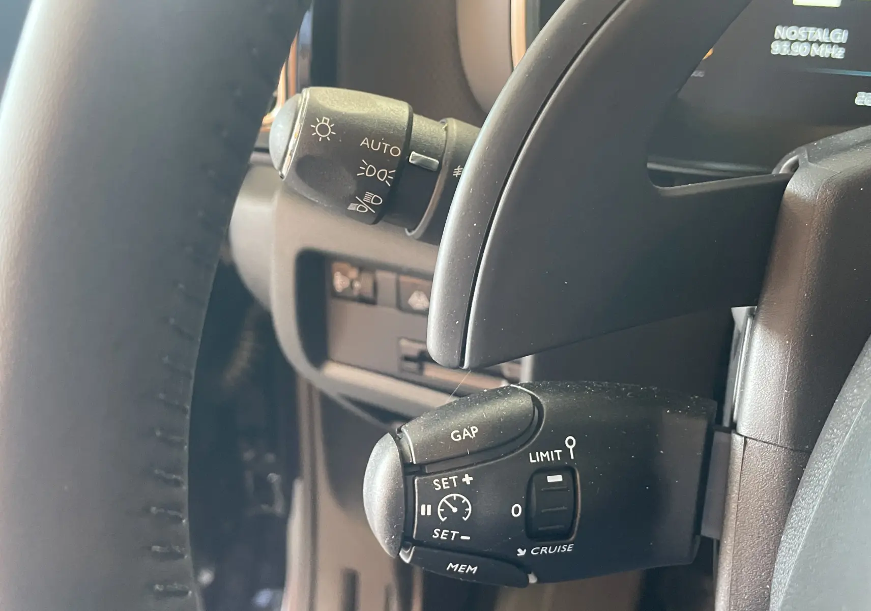 Gros plan sur la commande de régulateur de vitesse au volant du Citroën C5 Aircross hybride bleu foncé, intérieur côté gauche.