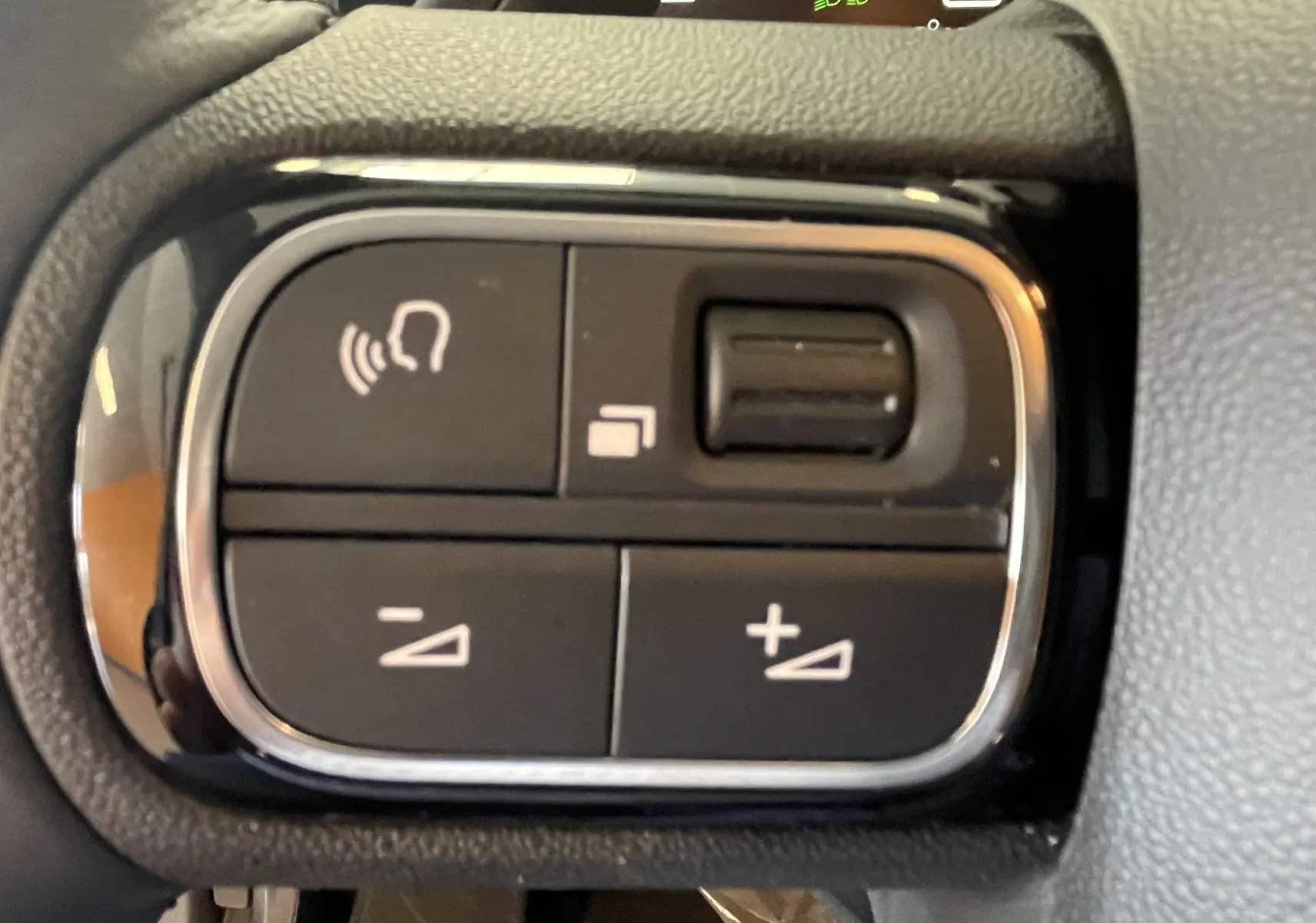 Gros plan sur les commandes au volant du Citroën C5 Aircross hybride 2025, boutons noirs avec cadre chromé.