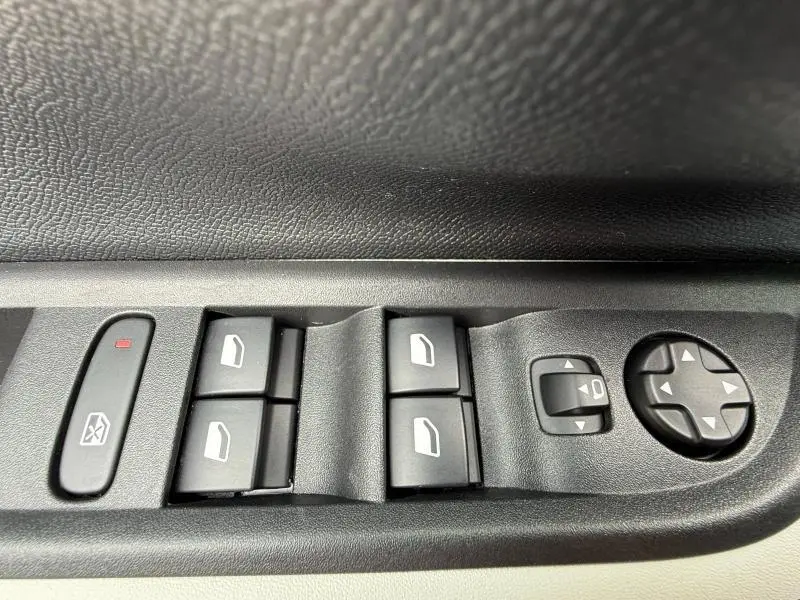 Gros plan sur les commandes de lève-vitres et réglage des rétroviseurs côté conducteur d'une Citroën C3 Gris Mercury.