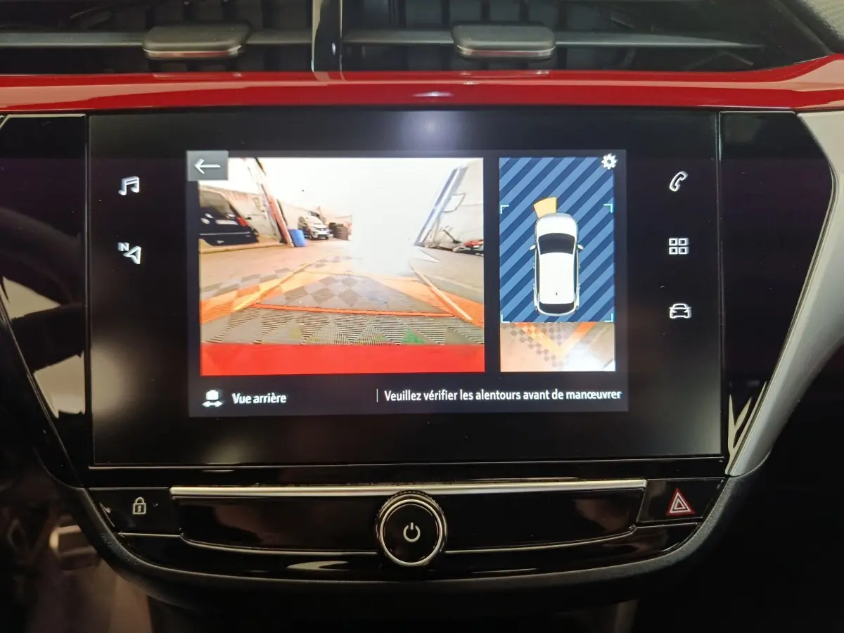 Écran tactile central de l’Opel Corsa rouge 2023 montrant la caméra de recul et l’aide au stationnement arrière.