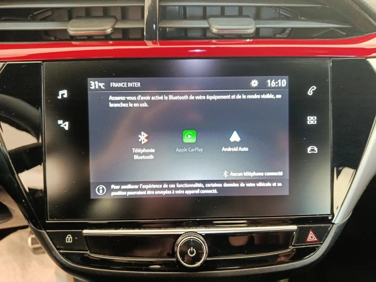 Écran tactile central de la console d’une Opel Corsa rouge, affichant les options Apple CarPlay et Android Auto.