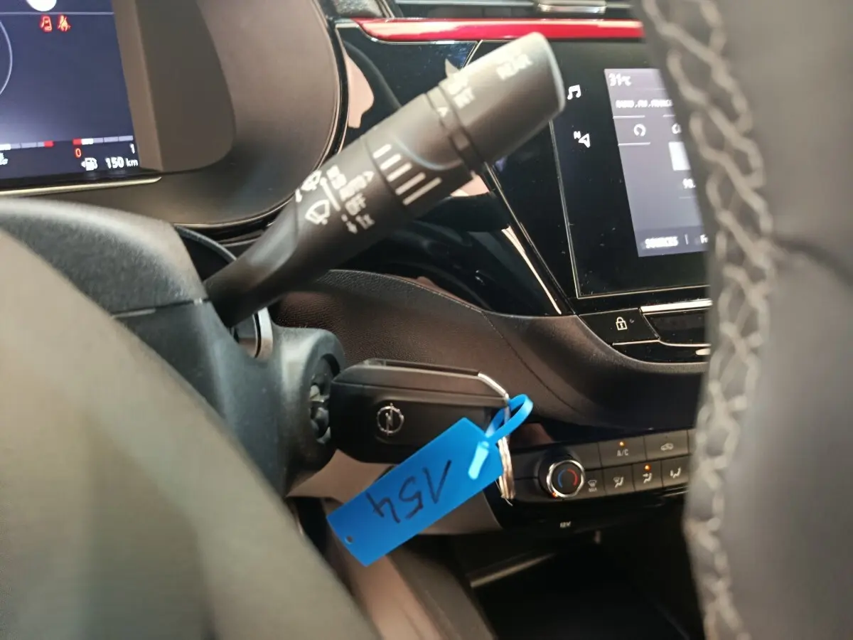 Vue intérieure rapprochée du volant cuir synthétique et de la clé dans le contact d’une Opel Corsa rouge 2023.