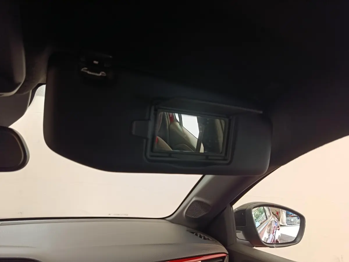 Vue intérieure côté conducteur de l'Opel Corsa rouge 2023, avec miroir de soleil ouvert et rétroviseur latéral visible.