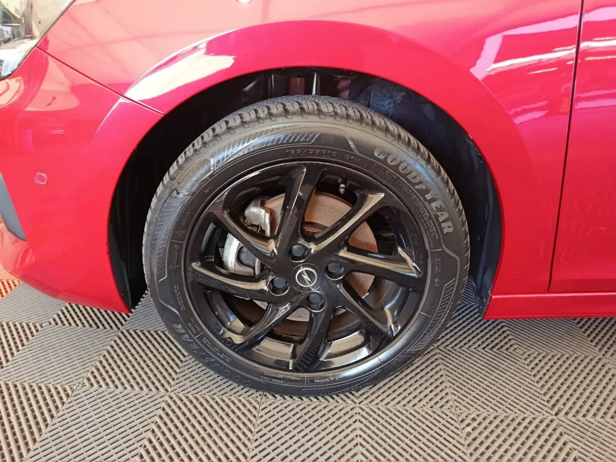 Gros plan sur la roue avant gauche noire d’une Opel Corsa rouge 2023 avec jante en alliage et pneu Goodyear.