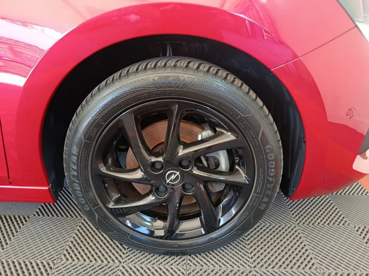 Gros plan sur la roue avant droite noire brillante d'une Opel Corsa rouge 2023, avec pneu Goodyear visible.